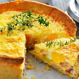 Bacon pie with flaky pastry and fresh thyme sprig garnish.