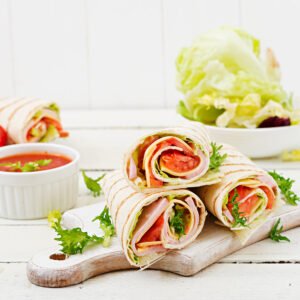 Ham and cheese roll with tomato and lettuce filling on a wooden board